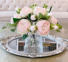 a bouquet of flowers in a glass vase on a table with a mirror behind it