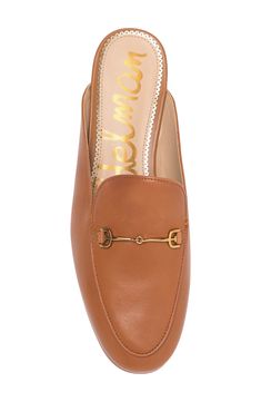 A glittery scalloped insole trim adds dainty style to this sleek mule that has brassy goldtone hardware and a subtle heel. Synthetic or leather upper and lining/rubber sole Imported Gold Slip-on Mules For Work, Gold Leather Mules For Spring, Gold Mules For Spring Workwear, Chic Mules With Leather Footbed And Almond Toe, Classic Low Heel Mules With Branded Insole, Chic Mules With Almond Toe And Leather Footbed, Classic Mules With Branded Insole And Low Heel, Gold Mules For Work, Chic Almond Toe Leather Mules