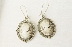 Victorian  cameo earrings. This lovely yet rose cameo earrings are just divine. This lovely piece of jewelry measures to fit a 25x18 inch cameo and comes with great antique toned french hook style dangle earrings. These gorgeous earrings measure 1 3/4 inches in length and would be the perfect gift for you or someone special. Cameo necklace: https://www.etsy.com/listing/460678090/victorian-cameo-necklace-personalized?ref=shop_home_active_2&pro=1&frs=1 https://www.etsy.com/listing/500220724/pink-c Victorian Earrings, Gifts Mom, Woman Jewelry, Cameo Earrings, Bronze Earrings, Cameo Jewelry, Jewelry Bridesmaid, Cameo Ring, Cameo Necklace