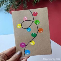 a hand holding up a card with colorful buttons on it