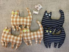 three cats made out of fabric sitting next to each other on a couch with buttons