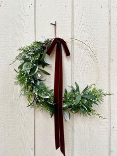 a wreath hanging on the side of a white wall with a red ribbon around it