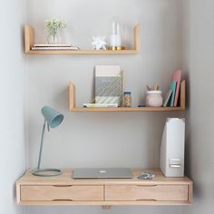 a laptop computer sitting on top of a wooden desk next to a shelf filled with office supplies