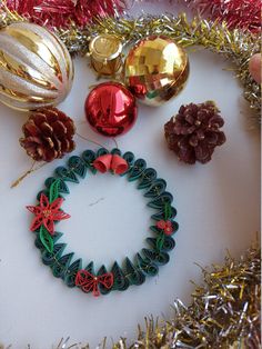 christmas ornaments are arranged on a table with tinsel, pine cones and other decorations