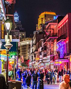 people are walking down the street at night in an urban area with tall buildings and neon lights