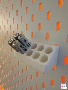 two batteries are attached to the wall with orange lights behind them and on top of each other