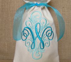 a white bag with blue ribbon and monogrammed letters on it, sitting on a table