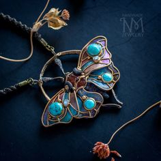 a butterfly shaped brooch sitting on top of a black table next to other jewelry