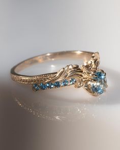 a gold ring with blue and white stones on it's side, sitting on a table