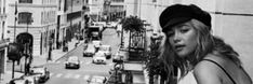 a black and white photo of a woman standing in the middle of a city street