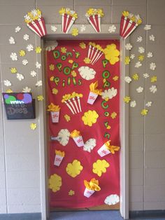 a red door decorated with popcorn and movie themed paper decorations on the front, along with yellow flowers