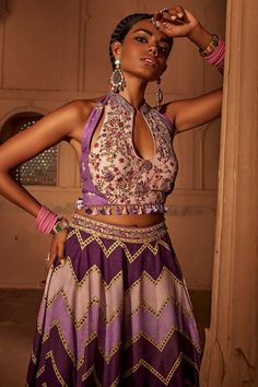 Lilac and purple sharara featuring geometrical prints. Comes with coordinated, intricately embroidered padded blouse with heavy tassels and doris at back.
Components: 2
Pattern: Printed
Type Of Work: Chevron Patterns
Neckline: Mandarin Notched
Sleeve Type: Sleeveless
Fabric: Raw Silk
Color: Purple
Other Details: 
Backless with tassel tie-up
Length:
Blouse: 14 inches
Sharara: 44 inches
Model height: 5ft 8inches, wearing size S
Note: All the jewellery worn by the model is not for sale
Occasion: De Purple Sharara, Geometrical Prints, Padded Blouse, Chevron Patterns, Chevron Print, Raw Silk, Set For Women, Aza Fashion, Model Height