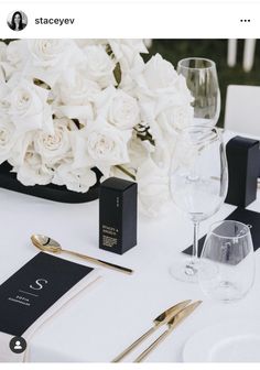 the table is set with white flowers and silverware