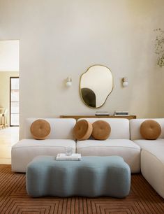 a living room with a couch, ottoman and mirror