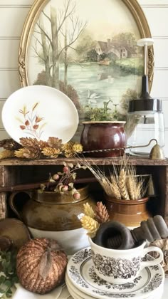 a table topped with plates and bowls filled with autumn decorating items on top of a wooden shelf