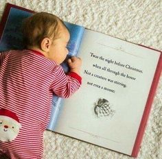 a baby is laying on the floor reading a book with santa clause written in it