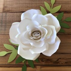 a paper flower with green leaves on a wooden surface