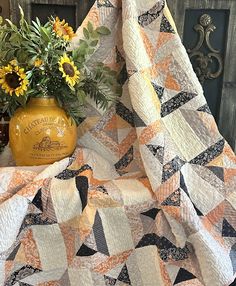 a vase with sunflowers sitting on top of a quilt