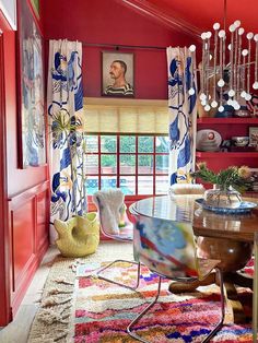 a living room with red walls and colorful rugs on the floor in front of a large window