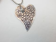 A totally unique stamped heart metal pendant. This metal heart is covered with random stamped hearts and adorned with tiny metal balls. To top it off, a metal or crystal bead is added to the top off the pendant. There are two color options - aluminum or copper. It is 24 inches long on lightweight chain. Metal Heart Necklace With Heart Beads, Metal Heart Necklace With Open Heart Shape, Metal Heart Necklace With Open Heart And Heart Beads, Metal Open Heart Necklace With Heart Beads, Silver Heart Pendant Jewelry With Heart Print, Metal Heart Charm Necklace, Metal Double Heart Necklace With Heart Charm, Double Heart Metal Necklace With Heart Charm, Nickel Free Metal Heart Necklace