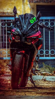 a red motorcycle parked in front of a building next to a metal fence and gate