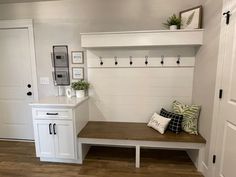 a bench with some pillows on top of it in front of a white cabinet and door