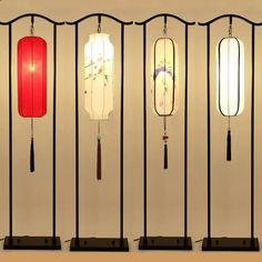 four lamps are hanging on the wall in front of each other with different designs and colors