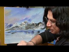 a woman is painting on an easel in front of a mountain range with snow