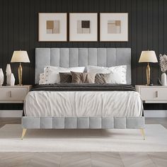 a large bed sitting next to two lamps on top of a wooden floor in a bedroom