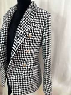 Stay warm in style with this Houndstooth Tweed Blazer. Crafted of heavyweight material, the blazer boasts two pockets and luxe gold buttons. The interior is lined for added comfort and warmth. You'll stay fashionable and cozy all season long. Winter Office Tweed Jacket With Houndstooth Pattern, Winter Houndstooth Tweed Jacket For Office, Winter Double-breasted Houndstooth Tweed Jacket, Tailored Outerwear With Gold Buttons For Fall, Elegant Houndstooth Blazer For Winter, Tweed Blazer With Houndstooth Pattern, Winter Business Tweed Jacket With Houndstooth Pattern, Winter Blazer With Houndstooth Pattern, Houndstooth Pattern Outerwear With Suit Collar For Fall