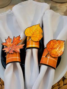 two napkins with fall leaves on them sitting on a plate