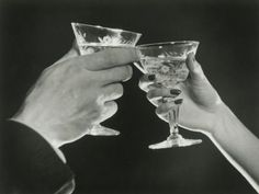 black and white photograph of two people toasting with wine glasses in front of them