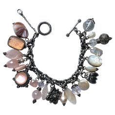 A lovely and fully loaded charm bracelet by famous jewelry designer Stephen Dweck. It features various size and shape faceted rose quarts and rock crystal bead, natural biwa and fresh water pearls, mother of pearl and sterling silver charms. The charms include Stephen Dweck's signature hand carved floral designs in two of the rose quartz and one mother of pearl cabochon stones. The bracelet has a toggle style clasp. It measures 8 inches flat with a wearable length of 7.5 to 7.5 inches. Next to t Elegant Beaded Dangle Charm Bracelet, Elegant Charm Bracelet For Jewelry Making With Natural Stones, Elegant Charm Bracelet With Natural Stones, Silver Rose Quartz Bracelet, Vintage Gemstone Beads Bracelet, Elegant Dangle Bracelets With Natural Stones, Silver Jewelry With Rose Quartz Gemstone Beads, Silver Rose Quartz Jewelry With Gemstone Beads, Elegant Natural Stones Dangle Bracelet