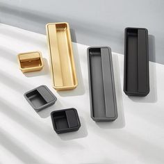 four different types of drawer pulls on a white surface, one black and one gold