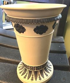 a white and black flower pot sitting on top of a wooden table