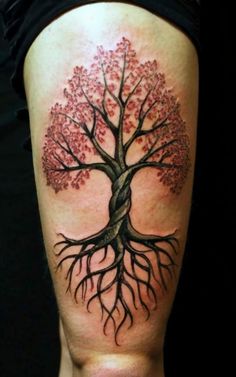 a woman's leg with a tree tattoo on the back of her thigh, which has pink flowers and leaves growing out of it