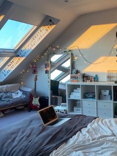 a bedroom with a laptop computer on the bed in front of an open skylight