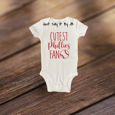 Cutest Phillies Fan baby bodysuit are perfect to wear on game day! Each bodysuit is white and available in short sleeve OR long sleeve. Each baby bodysuit is made with commercial grade iron on red vinyl. Bodysuit is available in 0-3 months, 3-6 months, 6-9 months, 12 months and 18 months. Baby bodysuit is made by Simple Joys By Carter. White Short Sleeve Bodysuit With Letter Print For Playtime, Short Sleeve Bodysuit For Playtime With Name Print, Playful Short Sleeve White Onesie, Playful White Short Sleeve Onesie, White Bodysuit With Name Print For Playtime, White Short Sleeve Bodysuit With Letter Print, White Short Sleeve Onesie For Game Day, White Letter-printed Short Sleeve Bodysuit, White Short Sleeve Bodysuit For Birthday