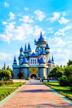 a large castle with blue turrets on it's sides and a brick walkway leading to the entrance