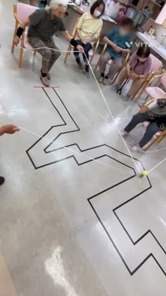 a group of people sitting in chairs around a drawing on the floor