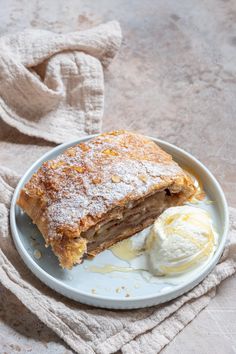 a piece of pie and ice cream on a plate with a towel in the background