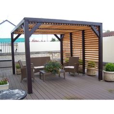 an outdoor patio area with chairs and a pergolan on the deck, surrounded by potted plants