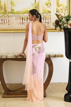 Step into the allure of pastels. The bright pink hue saree adorned with textured applique work highlighted with shiny crystals and beads crafts out a flower going all along attached with the pre-draped skirt. The shade of peach fuzz at the bottom of the silhouette brings a freshness of summer while the dainty detailing of crystal droplets all over the silhouette gives out a bling factor. Strapless bustier blouse adorned with applique work with the use of sparkling beads and crystals with an atta Hand Embellished Organza Pre-draped Saree, Pink Pre-draped Saree With Dupatta In Tissue Silk, Pink Hand Embellished Dupatta For Diwali, Hand Embellished Pink Dupatta For Diwali, Pink Organza Party Wear Pre-draped Saree, Pink Hand Embellished Georgette Dupatta, Hand Embellished Pink Georgette Dupatta, Bollywood Style Pink Hand Embellished Dupatta, Pink Bollywood Style Hand Embellished Dupatta