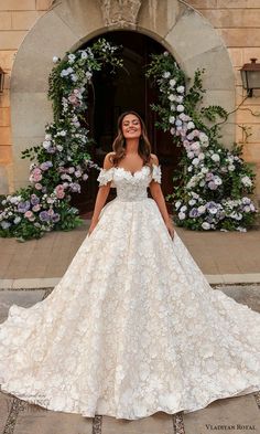 a woman standing in front of a doorway wearing a wedding dress with flowers on it