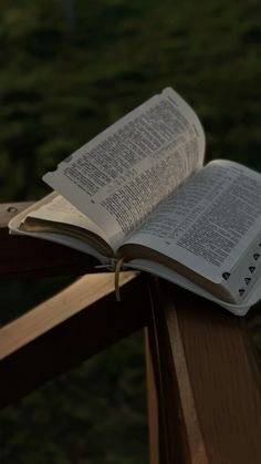 an open book sitting on top of a wooden bench