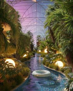 an indoor swimming pool surrounded by palm trees and plants with lights on the ceiling above it