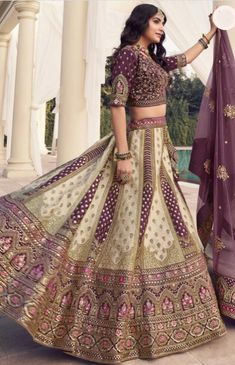 a woman in a purple and gold lehenga with her hand on the skirt