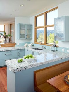 a large kitchen with blue cabinets and white counter tops, along with hardwood floors on both sides