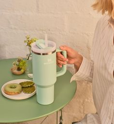 a woman sitting at a table holding a coffee mug