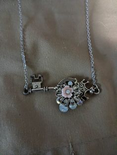 Flowers and opal stones adorn this crown key. Metal Key Pendant Jewelry, Key Pendant Jewelry In Metal, Vintage Pendant Jewelry With Keys, Vintage Metal Jewelry With Two Keys, Metal Jewelry With Keys For Gifts, Key Detail Metal Jewelry As A Gift, Vintage Metal Jewelry With Keys Detail, Vintage Metal Jewelry With Keys, Silver Key Pendant Jewelry